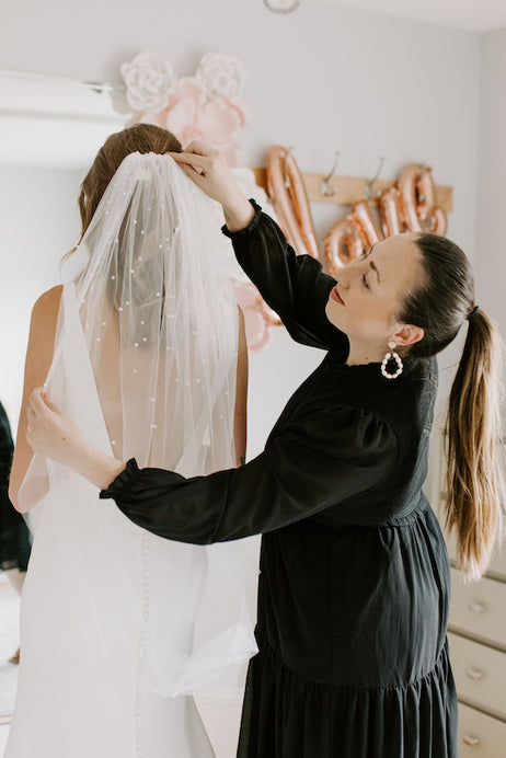 Wedding Shoppe Bridal Attendant assists a bride with her veil